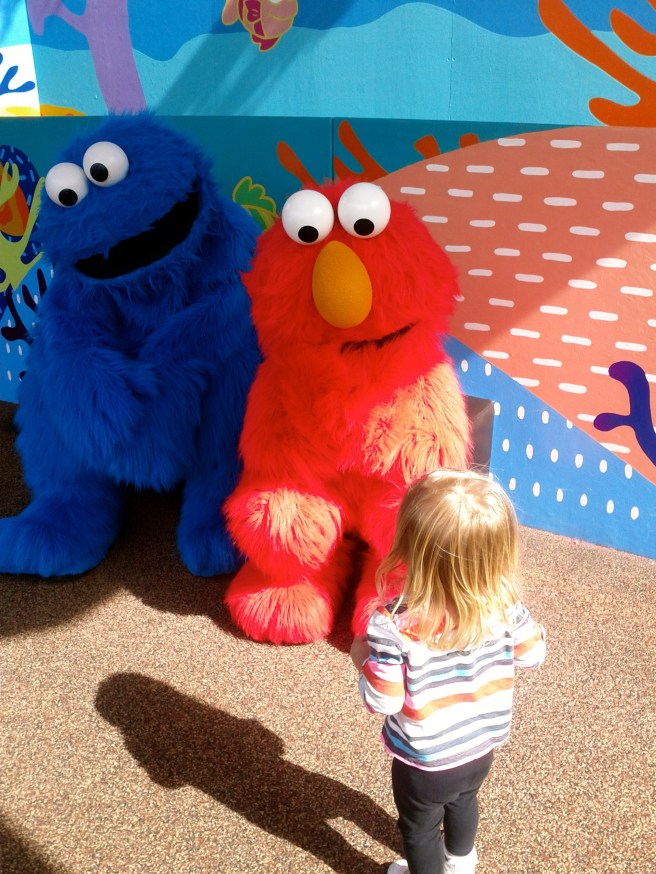 Kaili saw Elmo and ran to him but slowly backed away as he went for a high five.